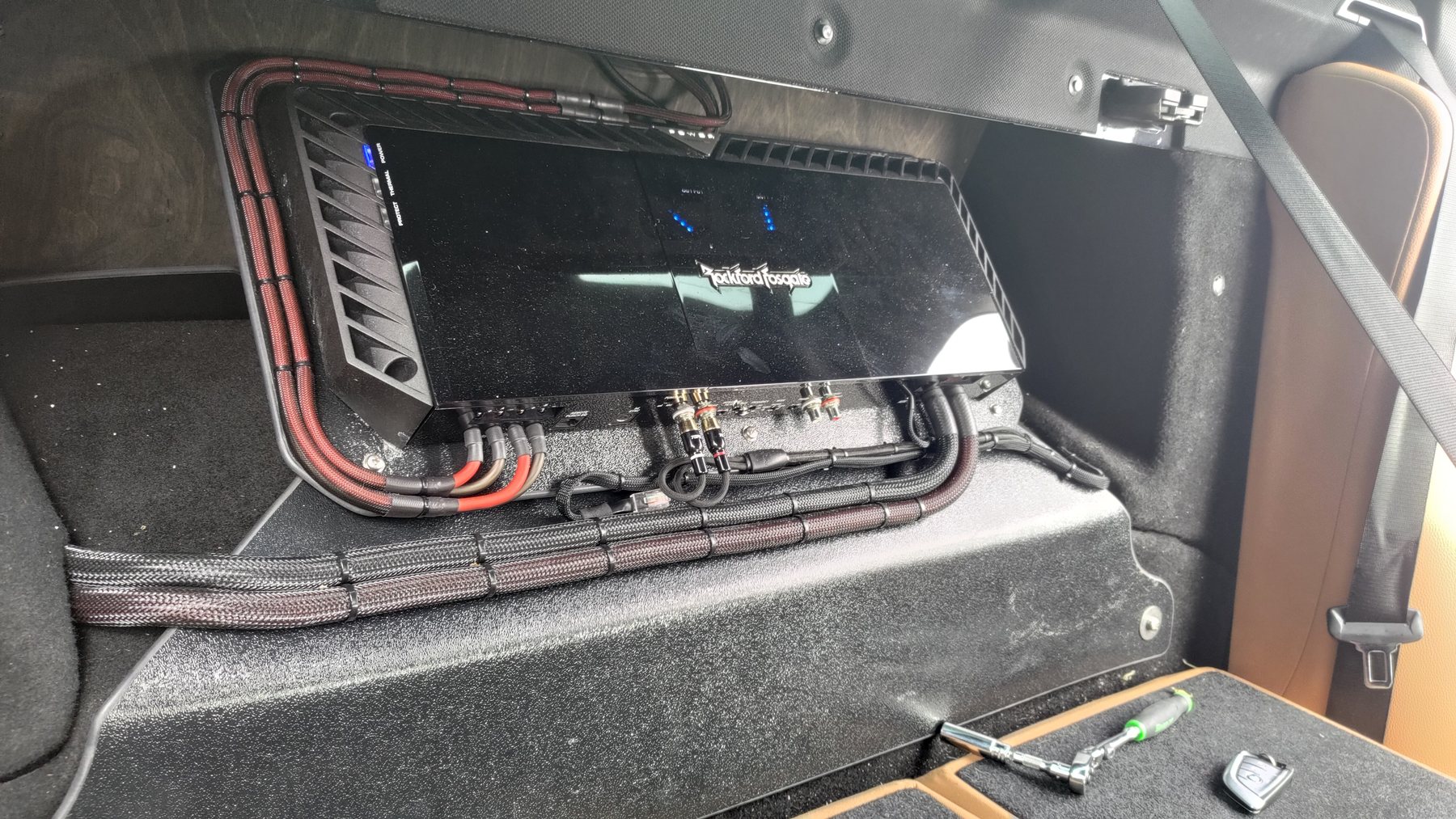 Amplifier mounted on a shaped carpeted panel with neatly routed wiring