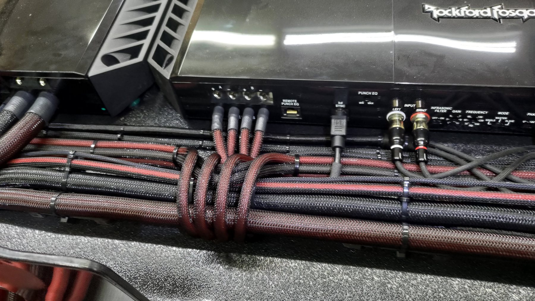 Parallel braided cable runs secured beneath an amplifier