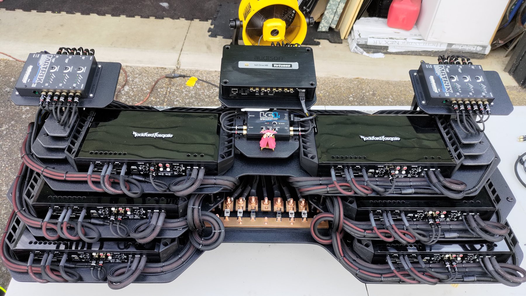 Layered amplifier and audio equipment rack with organized braided wiring on a workbench